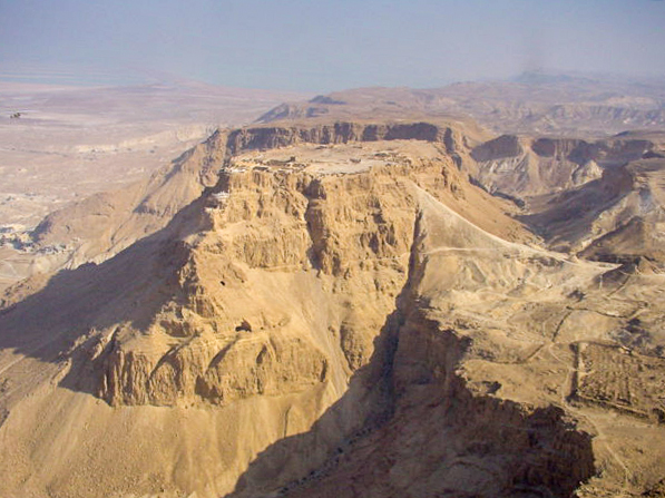 Vista aérea de la meseta aislada de Masada emergiendo sobre el Desierto de Judea con el Mar Muerto de fondo